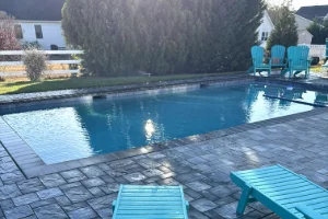 An inground swimming pool with pavers surrounding it