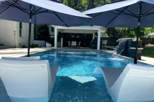An inground swimming pool with lounge chairs in front